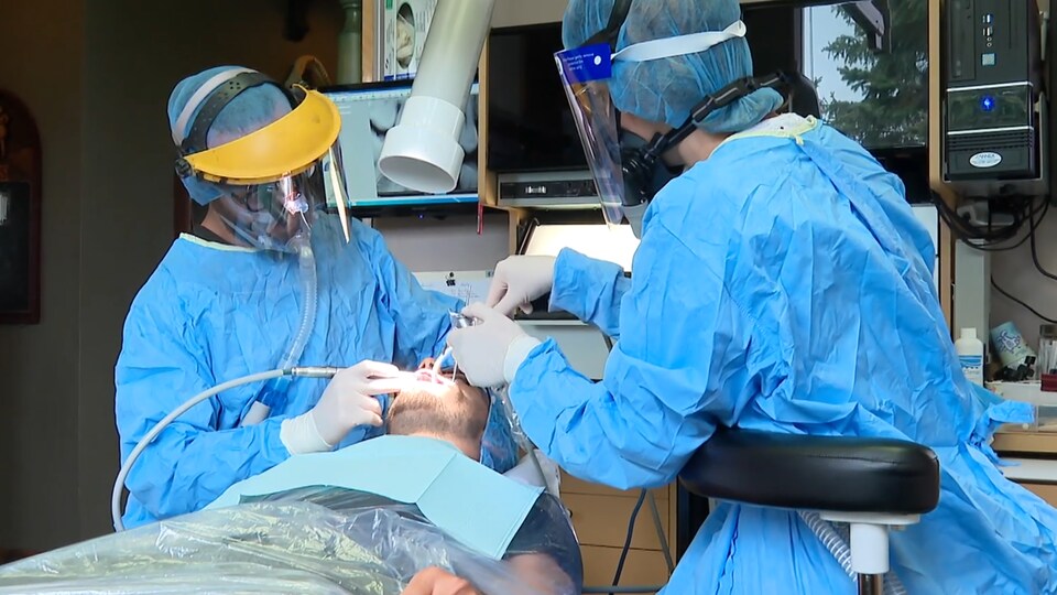 Deux dentistes traitent un patient. 