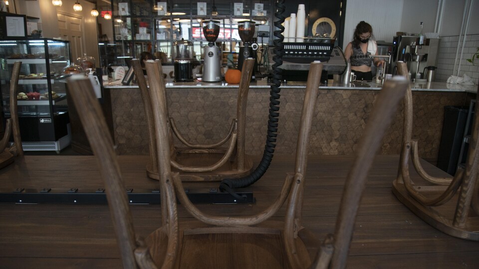 Des chaises disposées à l'envers sur une table dans un café.