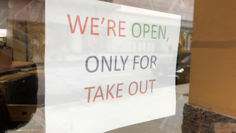 Une affiche qui dit « plats pour emporter seulement » sur la porte d'un restaurant.