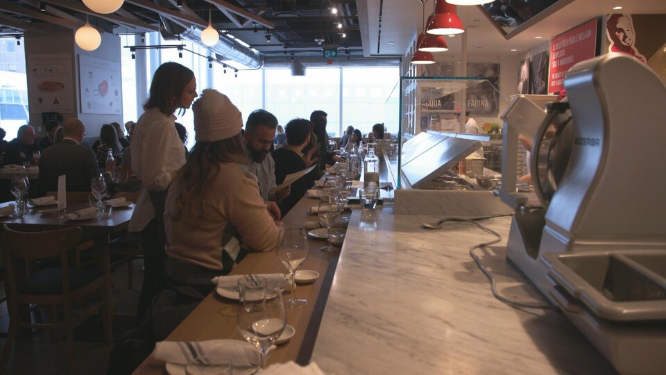 Une serveuse prend une commande au comptoir du restaurant Eataly à Toronto.