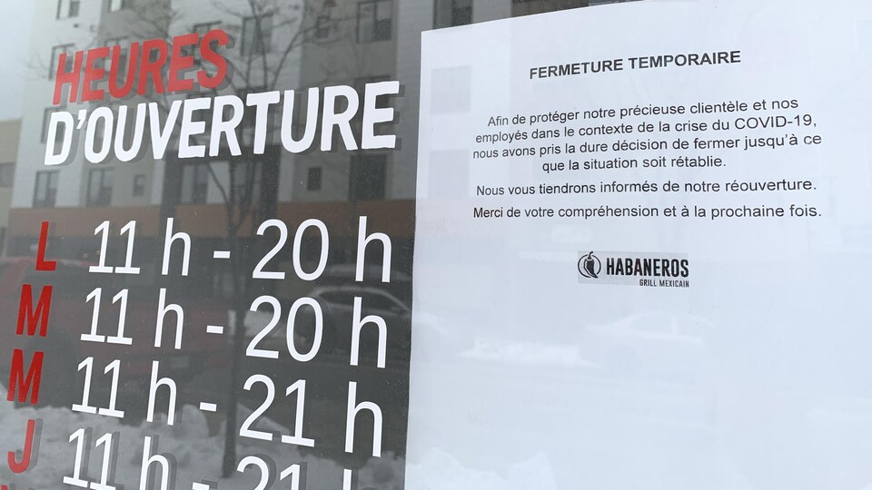 Une affiche dans la porte d'un commerce indique «fermeture temporaire».