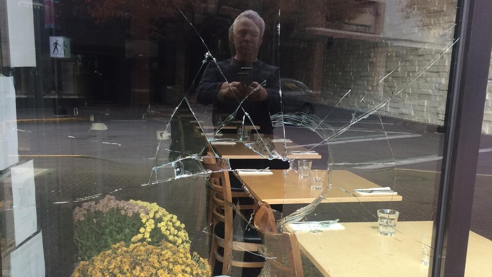 Des trous dans les fenêtres du restaurant avec le reflet de Gaétan Brousseau qui prend la photo.
