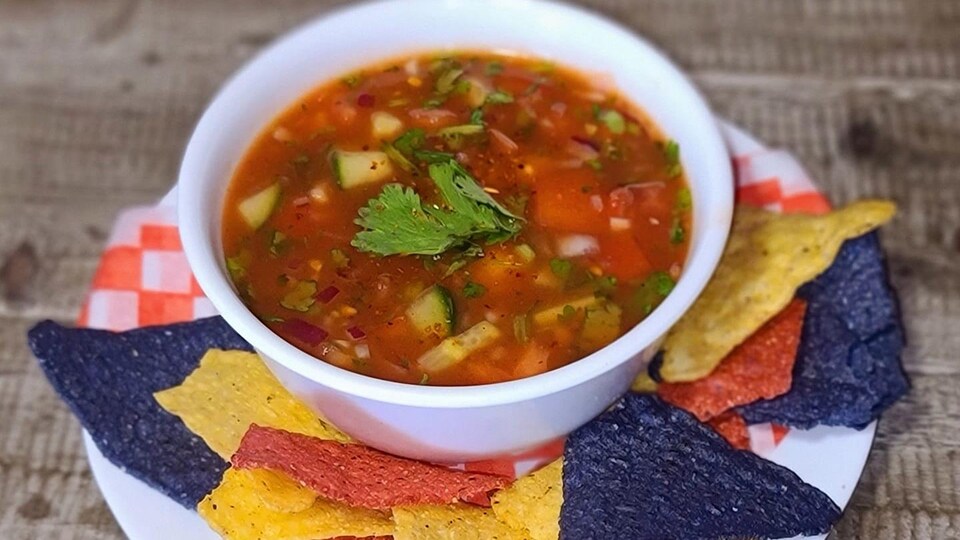 Un plat de soupe ceviche avec des nachos autour.