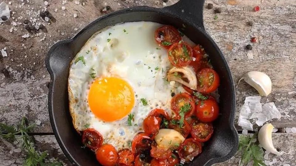 Une poêle en fonte avec un oeuf et des tomates cerises confites.