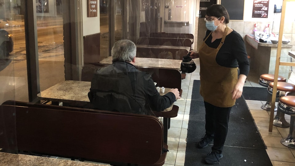 Une serveuse verse un café à un client.