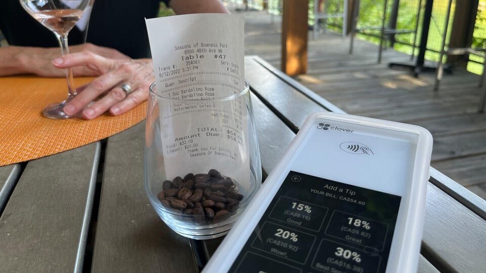 Une borne de paiement à côté d'une facture sur la table d'un restaurant.