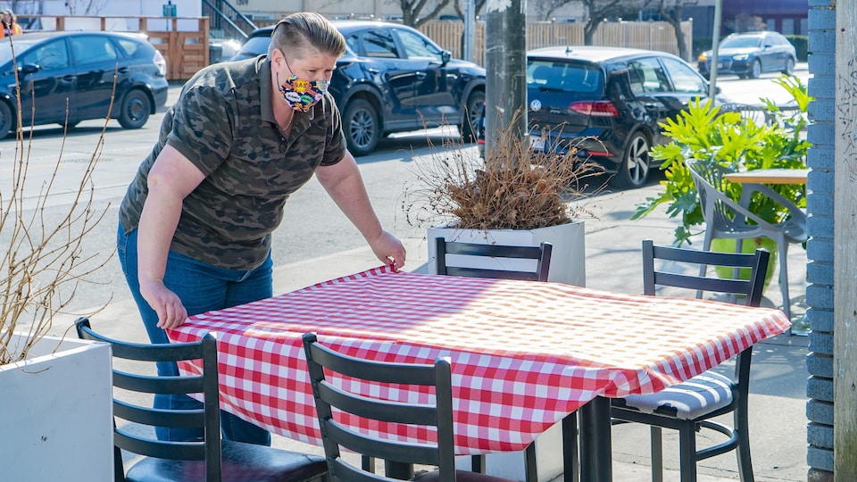 Une employée du restaurant torontois Gio Rana's Really Really Nice dresse une table sur une terrasse.