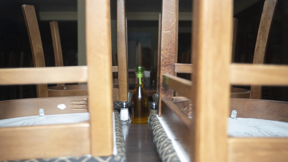 Une bouteille d'huile sur une table sur laquelle on a déposé des chaises à l'envers.
