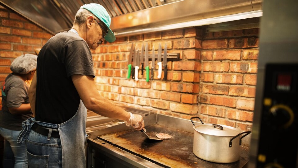 Un cuisinier faire cuire une boulette de boeuf haché.