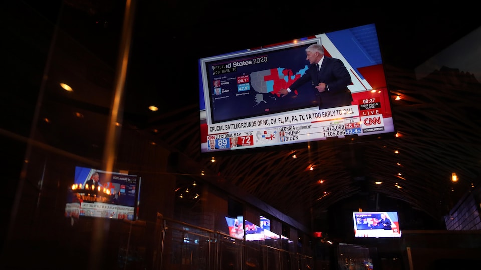 Plusieurs écrans dans un bar montrent des images de CNN.