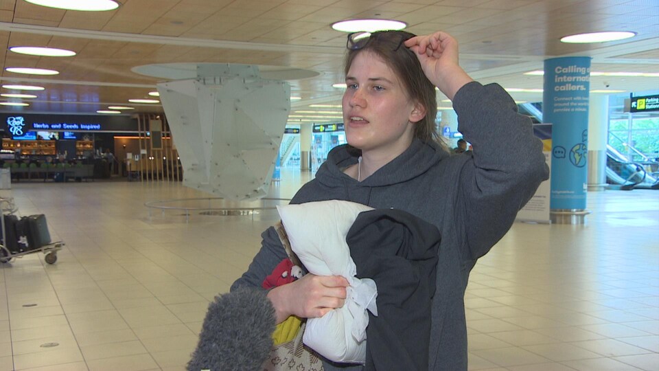 Gwen Mollins, tenant un oreiller à l'aéroport de Winnipeg. 