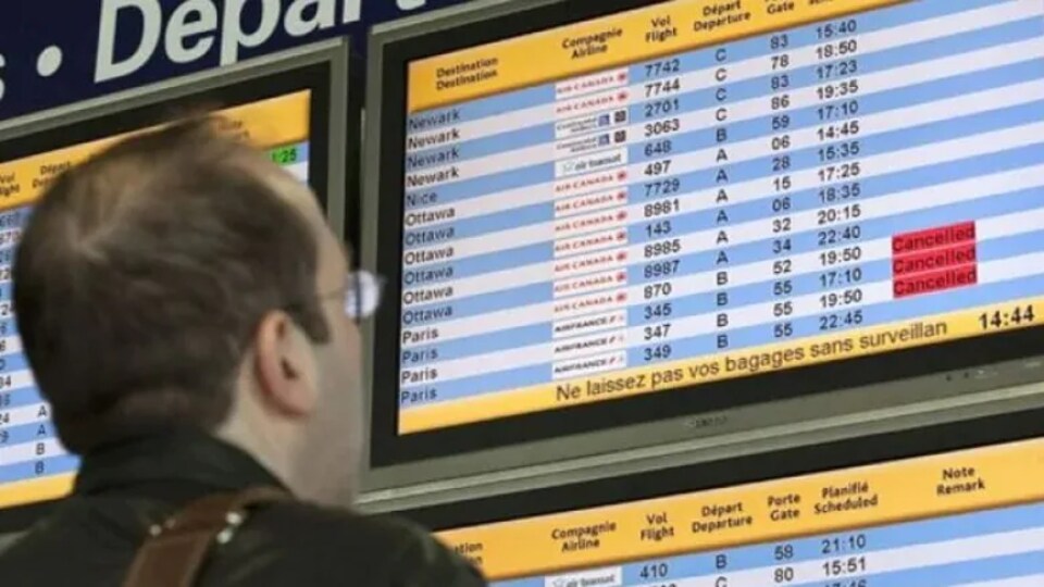 Un homme consulte la liste des vols affichée sur un écran dans un aéroport.