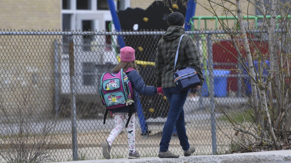 Une femme accompagne sa fille à l'école.
