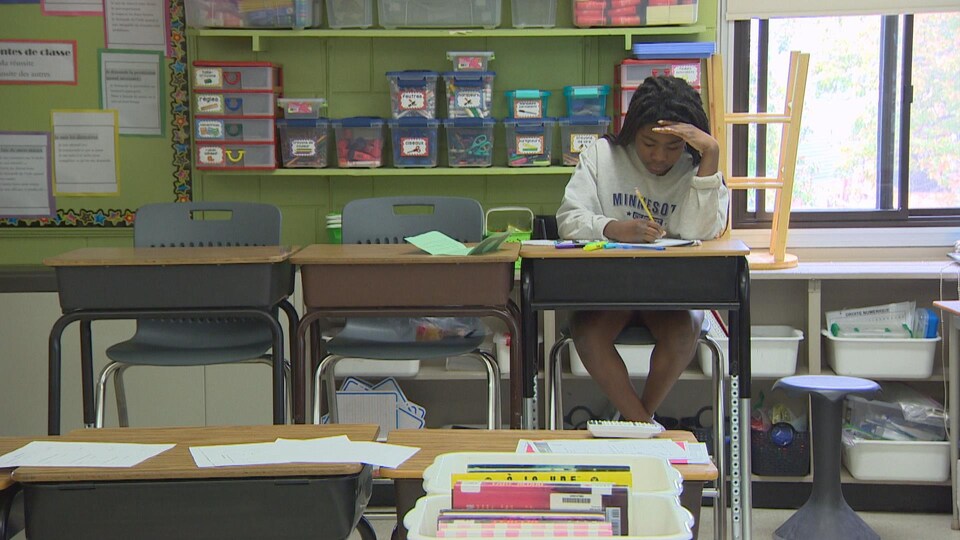 Une jeune fille assise à son bureau au retour en classe post-pandémie.