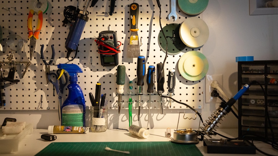 Une photo d'un atelier sur le mur duquel sont accrochés une panoplie d'outils.