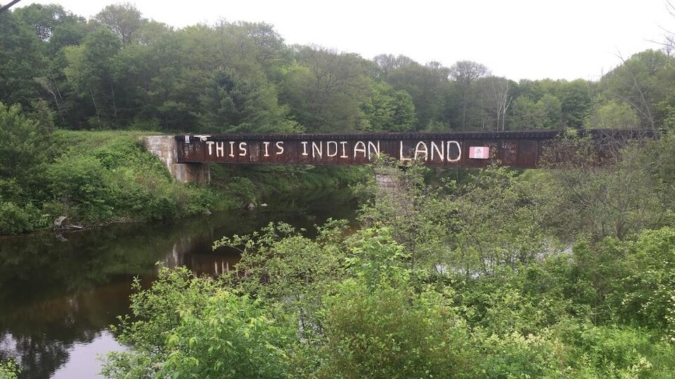 Un pont ferroviaire sur lequel est peint un immense graffiti « This is Indian land ».