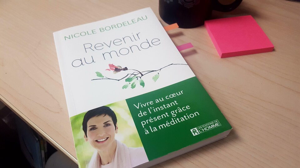 Le livre de Nicole Bordeleau, Revenir au monde, sur un bureau de travail.