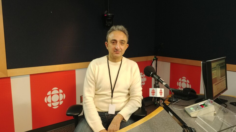 Reza Kamrani est assis dans le studio de Radio-Canada Vancouver avant son entrevue.