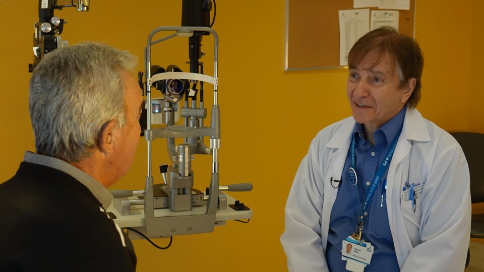 Le Dr Richard Bazin discute avec un patient dans une salle d'examen.