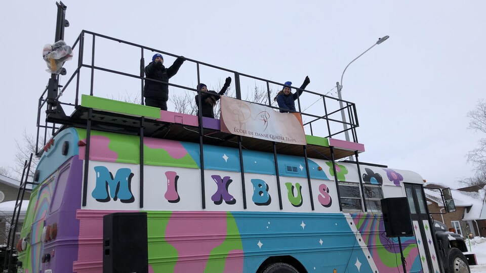 Des animateurs dansent sur le toit d'un autobus scolaire qui diffuse de la musique.