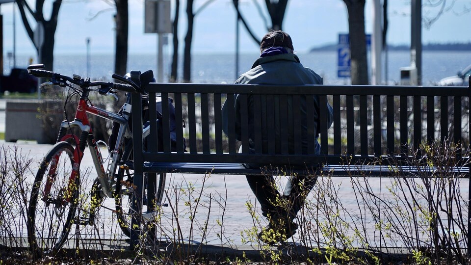 Une personne se repose sur un banc public, au centre-ville de Rimouski.