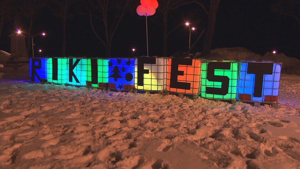 De gros blocs posés sur la neige sont illuminés, chacun a une lettre pour former le mot RikiFest.