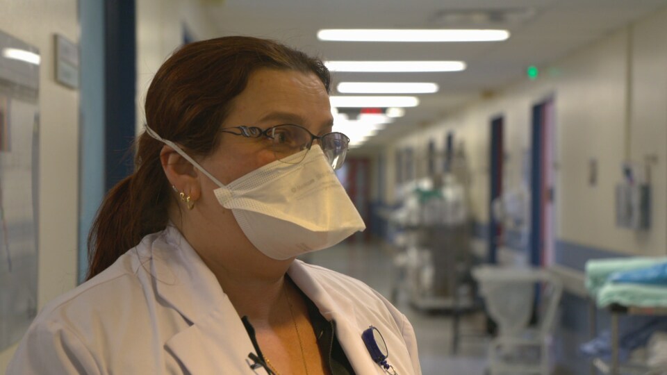 Une femme portant un masque et des lunettes dans un corridor d'hôpital