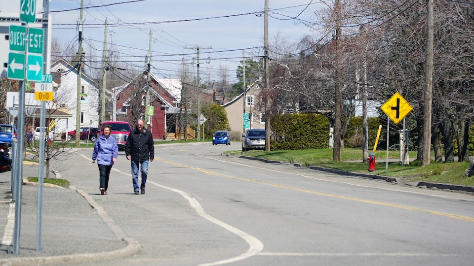 Deux personnes marchent sur un trottoir de Saint-Pascal.