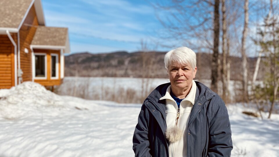 Une femme devant un lac l'hiver.