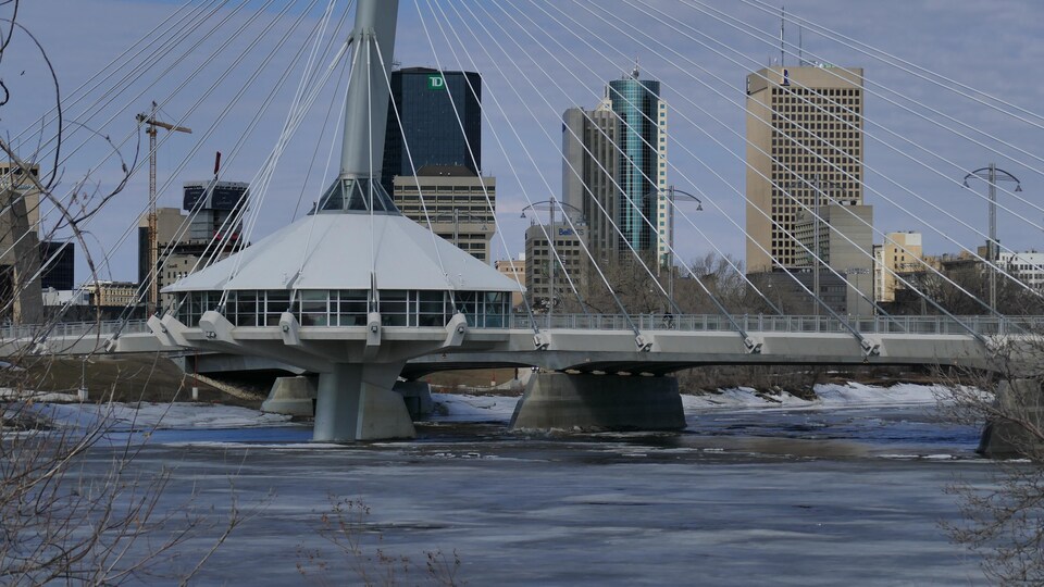 Une rivière, un pont et le centre-ville de Winnipeg à l'arrière-plan.