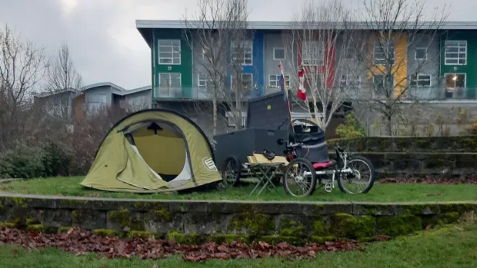 Une tente et un vélo cargo devant un immeuble.