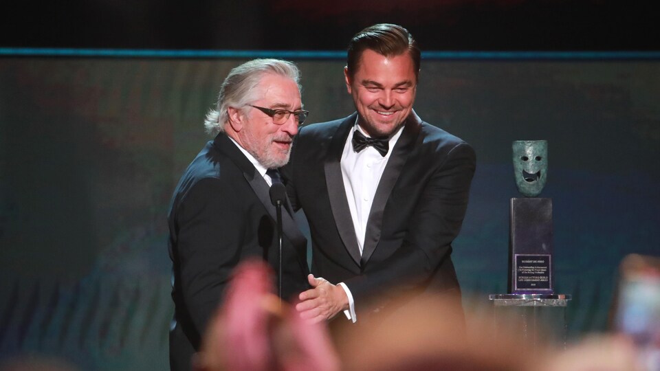 Robert De Niro et Leonardo DiCaprio vêtus de complets sont sur scène.