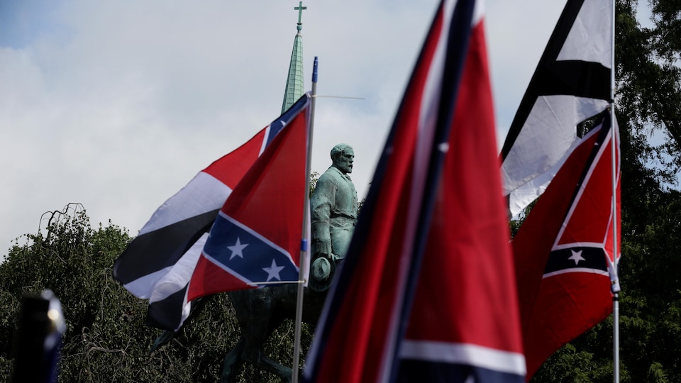 Des drapeaux des États confédérés du sud des États-Unis sont tendus dans le ciel devant une statue du général sudiste Robert E. Lee, à Charlottesville, le 12 août 2017.