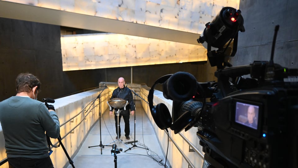 Un caméraman s'apprête à filmer Robert Len, joueur de handpan, sur l'une des passerelles au Musée canadien des droits pour la personne. 