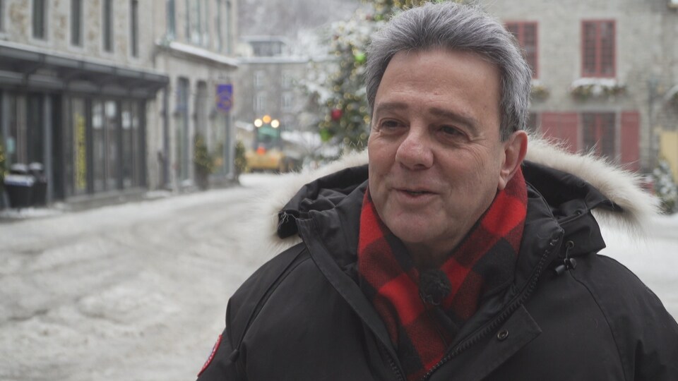 Un homme avec un manteau et une écharpe en entrevue dans le Vieux-Québec.