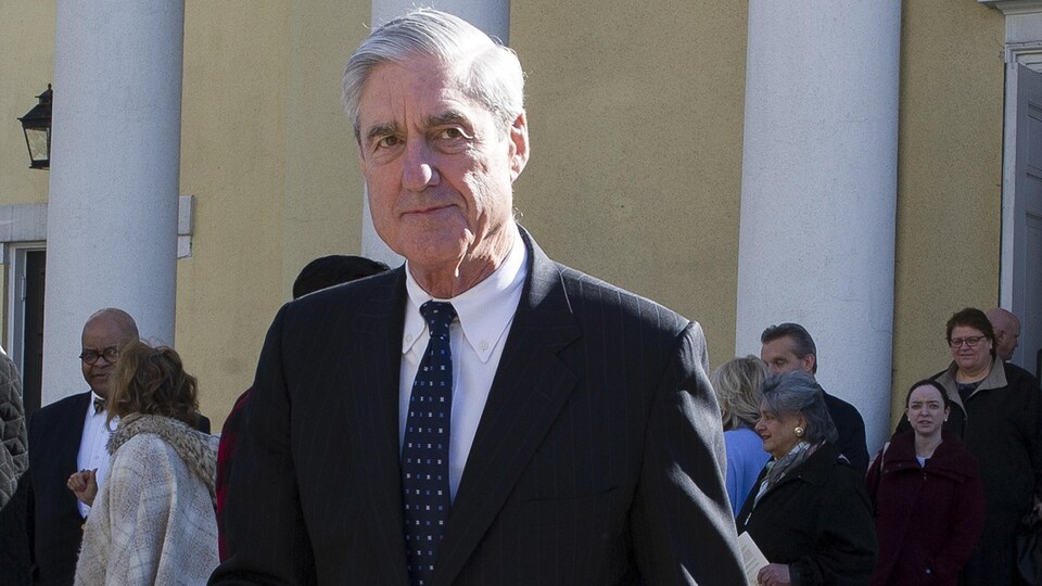 Robert Mueller est photographié à l'extérieur d'un bâtiment comportant de grandes colonnes blanches.