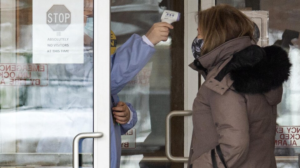 Une employée prend la température d'une femme à son arrivée au foyer de soins de longue durée Roberta Place.