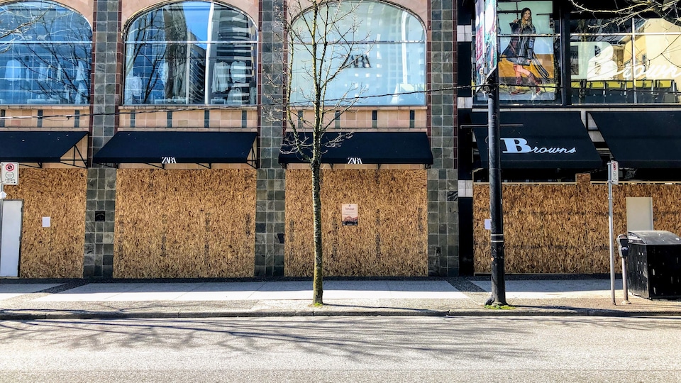 Les magasins Zara et Browns de la rue Robson sont fermés avec des planches de bois devant leur vitrine.
