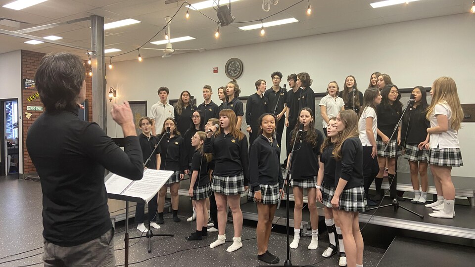 Des jeunes chantent. Ils sont dirigés par Roby Talbot. 