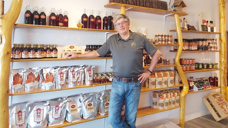 Roch Fortin debout devant les étagères de son magasin en Colombie-Britannique où il vend des produits de l'érable.
