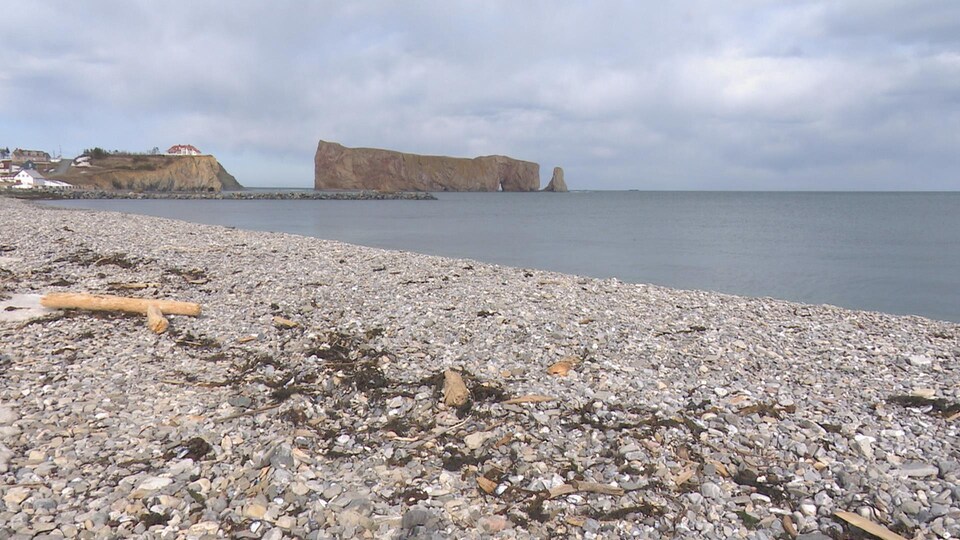 On aperçoit le rocher au loin, avec la plage en avant-plan.