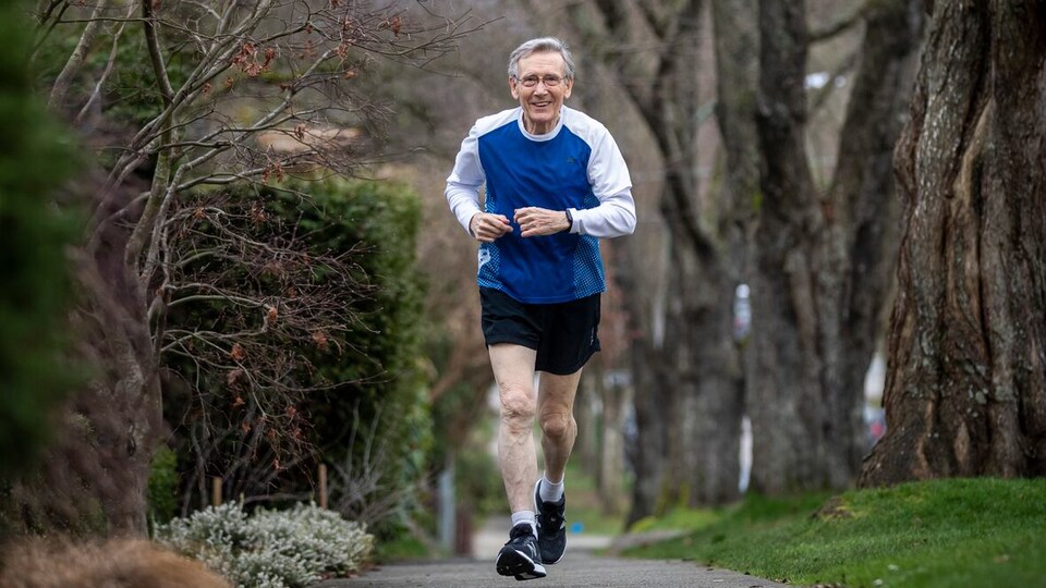 Rod Waterlow en train de courir en shorts sur un trottoir entouré d'arbres.