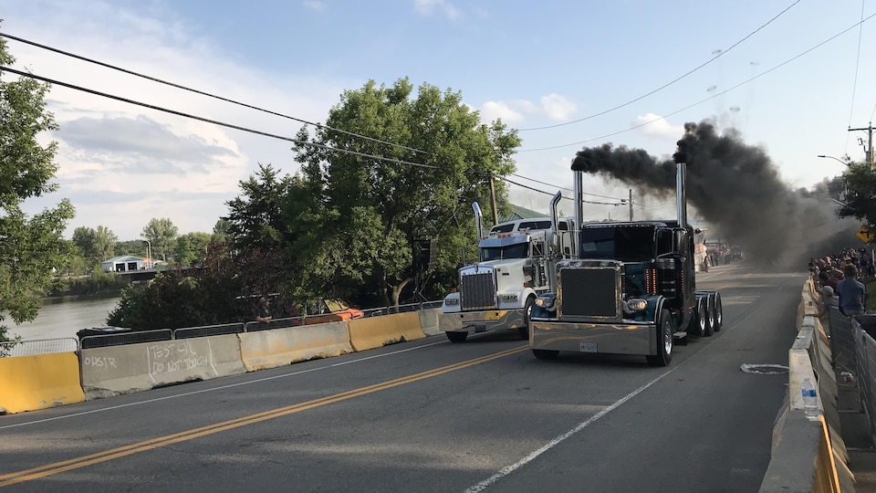 Deux camions font la course sur la piste d'accélération du 38e Rodéo du camion crachant leur fumée noire.