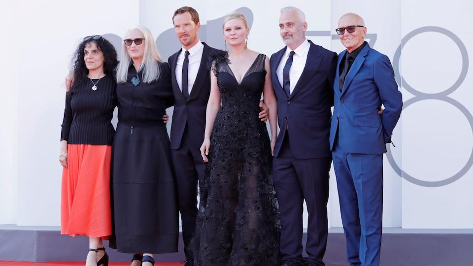 Trois femmes et trois hommes posent sur un tapis rouge.
