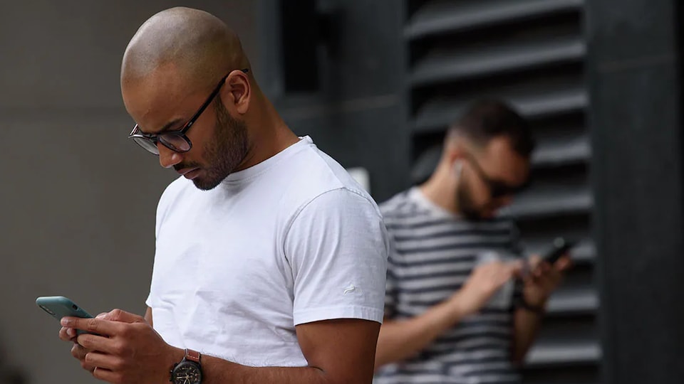 Deux hommes consultent des téléphones portables.