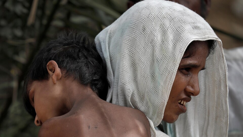 Une femme transporte un enfant malade dans un camp de réfugiés au Bangladesh.