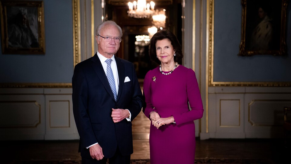 Carl XVI Gustaf et la reine Silvia, debout dans une salle du palais.