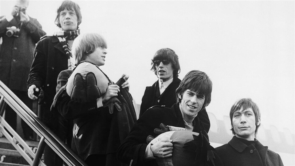 Les Rolling Stones débarquent d'un avion.
