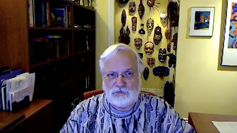 Un homme avec une barbe blanche et des lunettes en entrevue via vidéoconférence.