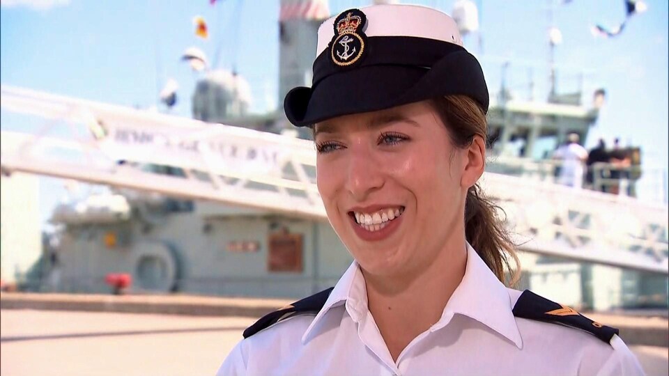 Rosalie Solomon, en uniforme de matelot, devant un navire.